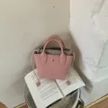 Detailansicht einer rosa Mini-Beuteltasche auf einem offenen Buch für das Lifestyle-Display - Mini / Rosa