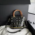 Glossy black bucket bag with bamboo handles and sequin floral details - Black