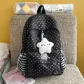 Close-up of black star-patterned backpack with white star plush pendant on a chair. - With Pendant / Black