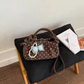 Detailed view of the brown polka dot handbag with decorative bow and pearl charm - Brown