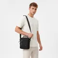 Detail of male model wearing a black casual crossbody bag with top handle and zippers - Black