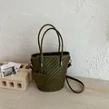 Detailed view of an olive green woven bucket bag with top handles and shoulder strap. - Green