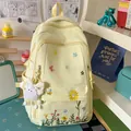 Yellow floral embroidered backpack with rabbit plush charm in a cozy desk setting - With Charm / Yellow