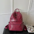 Close-up detail of a burgundy leather backpack with star-shaped strap design and rivets - Red