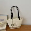 Detailansicht der gewebten Stroh-Tote-Bag mit Palmstickerei und schwarzen Griffen - Mit Anhänger / Gebrochenes Weiß