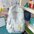 Light blue school backpack with floral embroidery and plush charm in a lifestyle study setting - With Charm / Blue