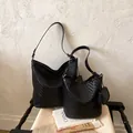 Close-up detail of black woven leather shoulder bag and bucket bag set in a lifestyle scene - L / Black