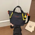 Handheld view of a minimalist black grid-patterned fashion yoga bag with yellow accents - Black