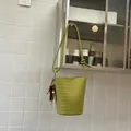 Large green woven bucket shoulder bag with decorative beaded tassel in a home setting - With Charm / Green