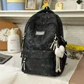 Close-up view of a black high-capacity student backpack with cute heart patterns and keychain - Black