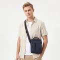 Caucasian male model wearing a navy blue crossbody bag in a casual summer outfit style - Blue