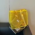 Modern yellow mesh tote bag and matching pouch set on architectural book background. - Large Capacity Grid Tote Bag Set / Yellow