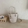 Detailed view of cream woven bucket bag with elegant dual handles and adjustable strap - Off White