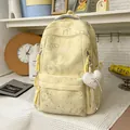 Detail of pastel yellow large capacity backpack with heart patterns and plush heart keychain - Yellow
