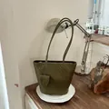 Stilvolle gewebte olivgrüne Tragetasche mit passendem Beutel auf einem Holztisch. - Grün