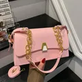 Close-up of a stylish pink square handbag with a thick gold chain and a chic metal clasp - Pink