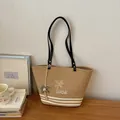 Detailansicht einer gewebten Stroh-Tragetasche mit Palmenstickerei auf Holztisch - Mit Anhänger / Khaki