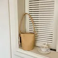 Elegant minimalist woven bucket bag displayed on a white wooden windowsill with a tea cup - With Charm / Yellow