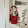 Red woven bucket bag with long handles and wooden bead charm on a windowsill - With Charm / Red