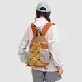 Back view of a stylish color-block outdoor backpack worn by a model in a light jacket - Caramel Brown