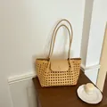Nahaufnahme einer gewebten braunen Tasche mit langen Trägern auf einem Holztisch - Bernstein