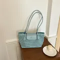 Detailansicht der eleganten Webstruktur einer hellblauen Schultertasche auf Holz. - Eisschmelzblau