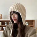Warme cremefarbene Strickmütze mit Ohrenklappen für den Winter am asiatischen Model. - 56-59cm (Elastisch) / Beige