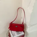 Chic red baguette bag displayed on a designer book for a minimalist French aesthetic. - Red