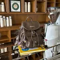 Close-up of a vintage brown faux leather backpack with a cute dog charm in a cafe - With Pendant / Dark Coffee