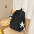 Stylish black backpack with starry print and white star pendant on a wooden chair - With Charm / Black