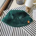 Detailed view of a dark green faux fur bucket hat for winter on a striped surface - Malachite green