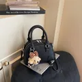 Close-up of a black leather Boston handbag with a cute dog charm on books - With Bear Charm / Black