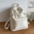 Cream white fashion backpack with unique star strap design and studded side pockets. - White