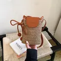 Hand holding a minimalist woven straw crossbody phone bag with a brown leather flap detail - Straw Woven Patchwork / Khaki