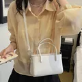 White minimalist rectangular women's handbag styled as a crossbody bag on a model in a casual setting - White