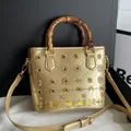 Elegant gold patent leather bucket bag featuring a vintage bamboo handle and floral beading - Gold