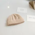 Detailed view of a minimalist beige ribbed knit short beanie on a clean white surface - 54-58cm / Beige
