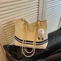 Large cream woven tote bag featuring navy blue stripes and stylish gold chain straps for women - Blue