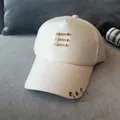Casquette de baseball blanche au fini satiné avec anneaux métalliques et clous dorés. - Beige