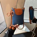 Close-up of a blue denim and brown leather crossbody phone bag with knotted strap - Denim Patchwork / Blue