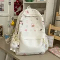 Close-up detail of white cute backpack featuring cartoon animal patterns and a plush keychain - With Charm Style / White