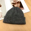 Detailansicht einer dunkelgrauen Strickmütze mit Distressed-Details am Umschlag. - Universalgröße / Grau