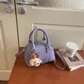 Detail view of a stylish purple textured Boston bag with a cute dog plush charm - With Bear Charm / Purple