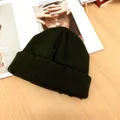 Detailaufnahme einer dunkelgrünen Strickmütze mit strukturierter Textur auf Holz - Universalgröße / Armeegrün