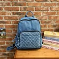 Lässiger Jeansrucksack mit Steppmuster und Quasten-Details auf einem Holztisch - Mittelblau