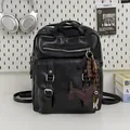 Detail view of a black large capacity travel backpack with a cute dog-shaped keychain. - With Charm / Black