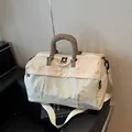 Vue latérale d'un sac de voyage beige avec panneau avant texturé et anses brunes - Blanc Cassé