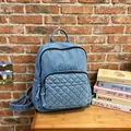 Moderner hellblauer Denim-Rucksack mit Stepptasche vor einer gemütlichen Ziegelwand - Hellblau