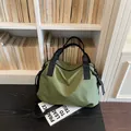 Dettaglio di una grande borsa da viaggio a scacchi verdi davanti a una libreria bianca - Verde