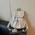 Detalle de una mochila gris claro con cordón, bolsillos plisados y patrón de cuadrícula - Gris